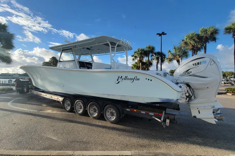  Yacht Photos Pics 2022 Yellowfin 42 Offshore boat on trailer, parked near palm trees under a blue sky.