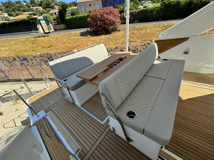  Yacht Photos Pics 2025 Jeanneau DB/37 IB boat interior with cushioned seating and wooden deck.