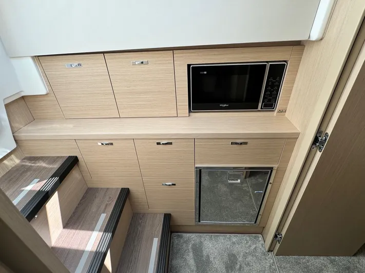  Yacht Photos Pics Modern interior of 2025 Jeanneau DB/37 IB yacht with microwave and storage cabinets.