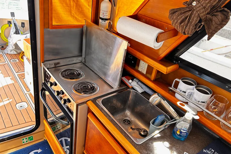  Yacht Photos Pics 2014 Cutwater C-28 boat kitchen with stove, sink, and wooden cabinetry.