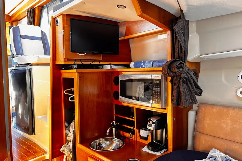  Yacht Photos Pics 2014 Cutwater C-28 interior with TV, microwave, and coffee maker in wooden cabinetry.