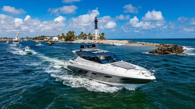 El Mar V Yacht Photos Pics 2022 Riviera 6000SY yacht cruising near a lighthouse on a sunny day.