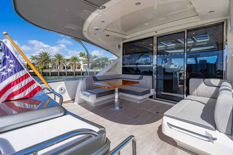 El Mar V Yacht Photos Pics Luxury 2022 Riviera 6000SY yacht deck with seating, table, and American flag.