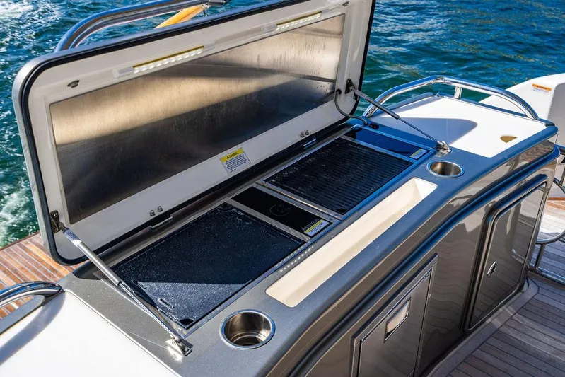 El Mar V Yacht Photos Pics Riviera 6000SY 2022 yacht outdoor kitchen with grill and sink, set against ocean backdrop.