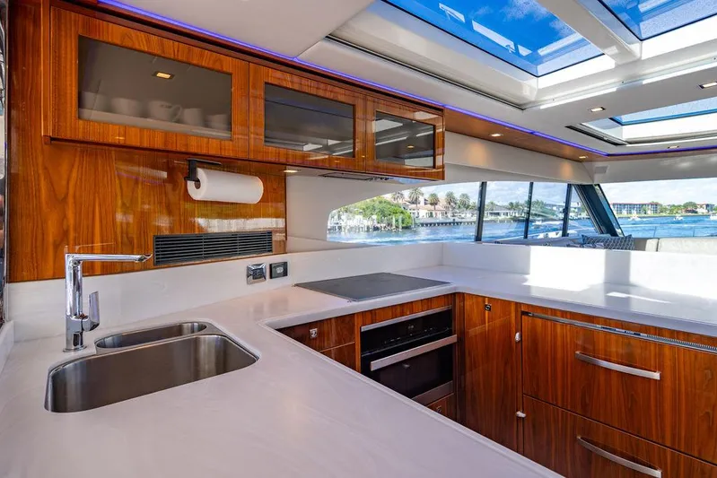 El Mar V Yacht Photos Pics Luxurious 2022 Riviera 6000SY yacht kitchen with sleek wood cabinetry and modern appliances.