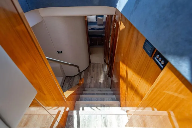 El Mar V Yacht Photos Pics Staircase inside 2022 Riviera 6000SY yacht with wooden paneling and modern design.