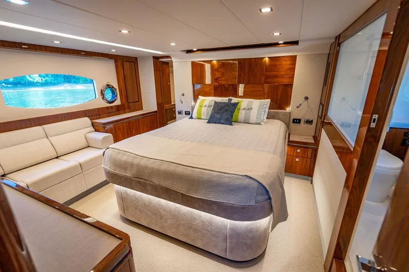 El Mar V Yacht Photos Pics Luxurious bedroom interior of 2022 Riviera 6000SY yacht with elegant wood finishes.