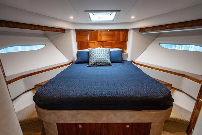 El Mar V Yacht Photos Pics Luxurious 2022 Riviera 6000SY yacht bedroom with elegant wood accents and plush bedding.