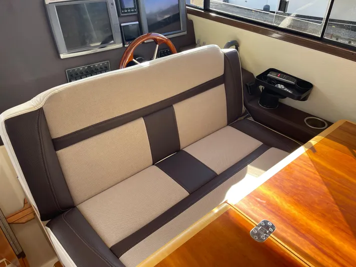  Yacht Photos Pics Interior seating of 2015 Cutwater 30 CB boat with wooden table and steering wheel.