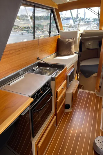  Yacht Photos Pics Interior of 2015 Cutwater 30 CB boat with wood finish and compact kitchen area.