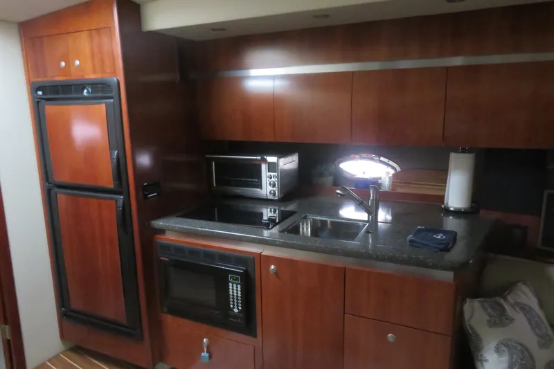 Swept Away Yacht Photos Pics 2007 Cruisers Yachts 420 Express kitchen with wood cabinetry, sink, and appliances.