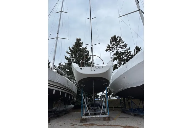 Targa Yacht Photos Pics 2008 Beneteau First 10R sailboat on dry dock, surrounded by trees and other boats.