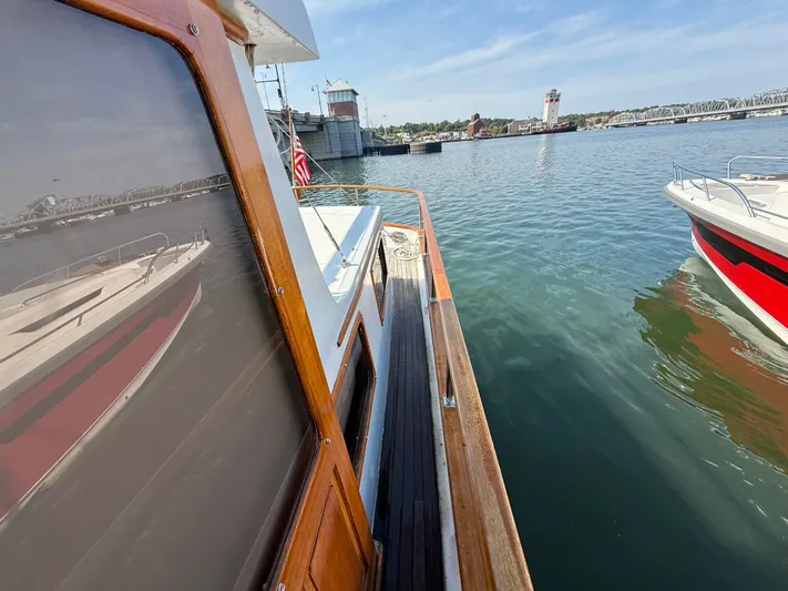 Aja Marie Yacht Photos Pics 1986 Marine Trader Tri Cabin yacht docked, reflecting water and nearby boats under clear sky.