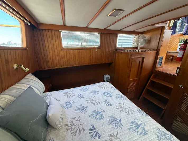 Aja Marie Yacht Photos Pics 1986 Marine Trader Tri Cabin bedroom with wood paneling, bed, and stairs.