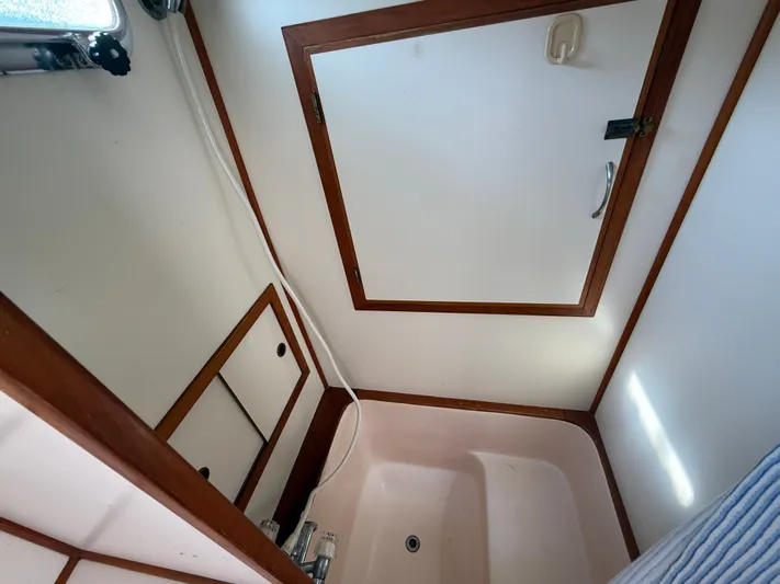 Aja Marie Yacht Photos Pics 1986 Marine Trader Tri Cabin bathroom with shower, white walls, and wooden trim.