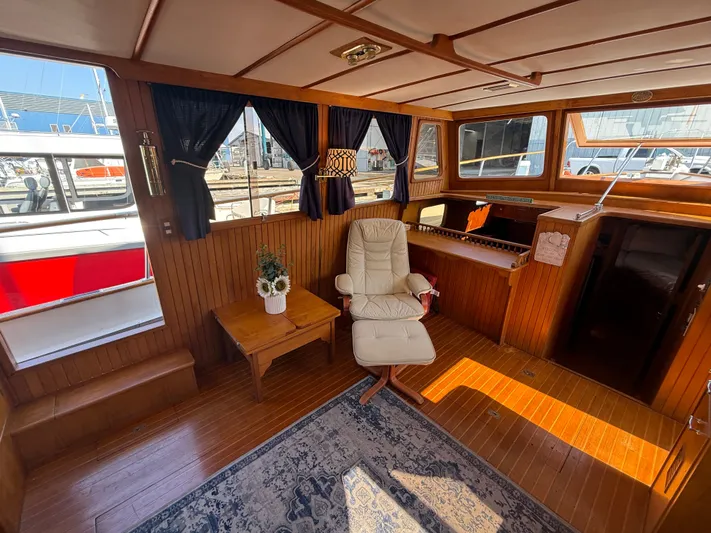 Aja Marie Yacht Photos Pics 1986 Marine Trader Tri Cabin interior with wood paneling, chair, table, and windows.
