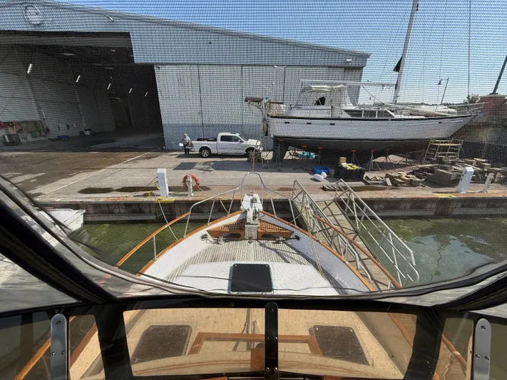 Aja Marie Yacht Photos Pics 1986 Marine Trader Tri Cabin docked near a shipyard with a large boat in the background.