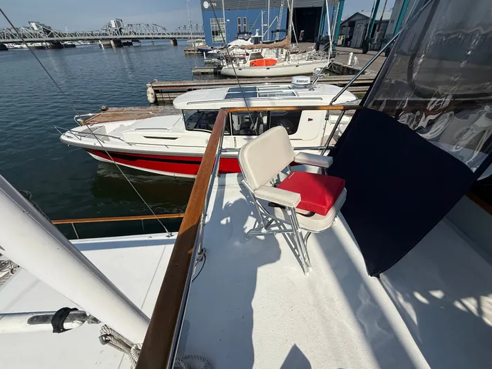 Aja Marie Yacht Photos Pics 1986 Marine Trader Tri Cabin yacht docked, featuring a deck chair with red cushion.