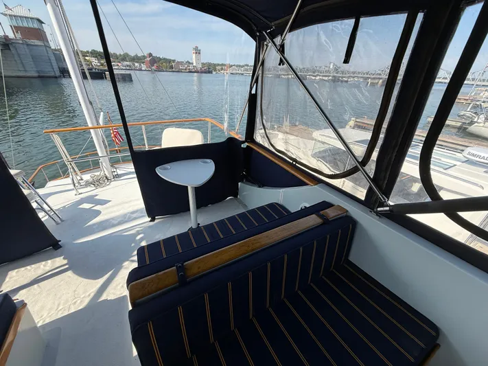 Aja Marie Yacht Photos Pics 1986 Marine Trader Tri Cabin yacht deck with seating, table, and waterfront view.