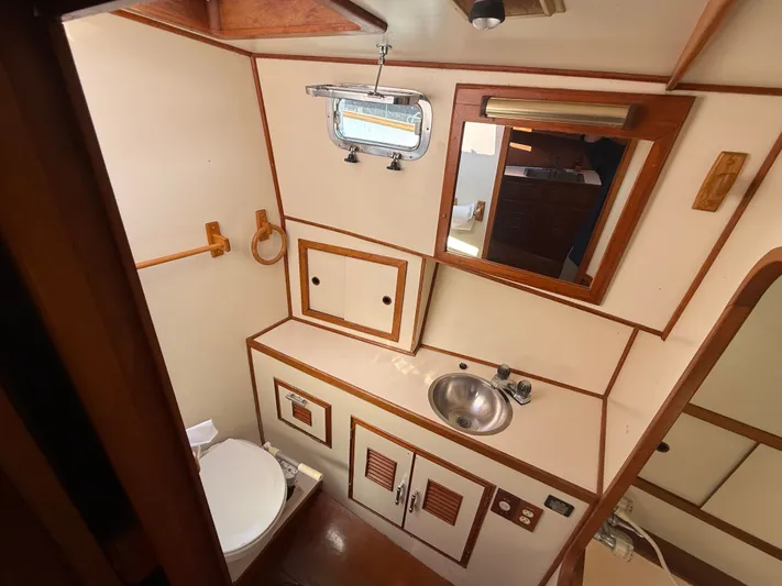 Aja Marie Yacht Photos Pics 1986 Marine Trader Tri Cabin bathroom with sink, mirror, and toilet.