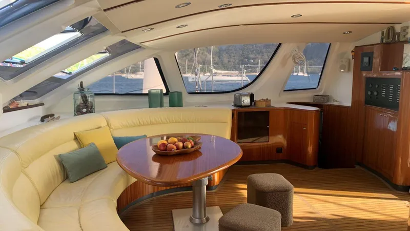 Mersea Yacht Photos Pics Luxurious Catana 582 yacht interior with curved seating, wooden table, and scenic windows, 2001 model.