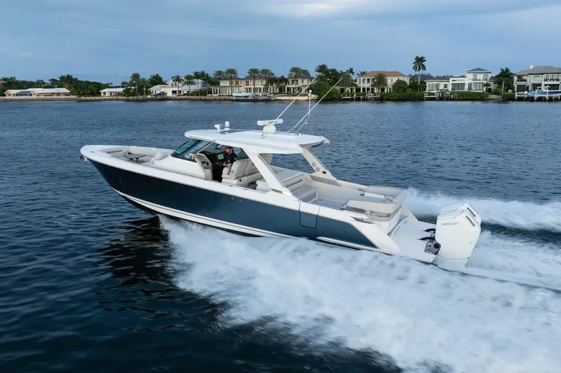 Twelve Yacht Photos Pics 2022 Tiara Sport 43 LS boat cruising on a serene waterway near luxury homes.