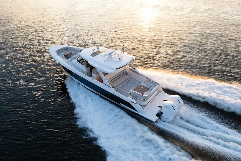 Twelve Yacht Photos Pics 2022 Tiara Sport 43 LS luxury boat cruising on open water at sunset.