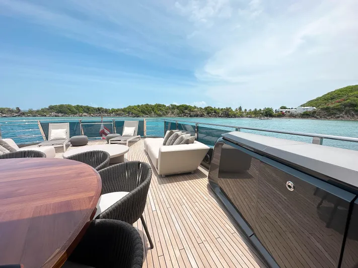 Hang Loose Yacht Photos Pics Luxurious 2021 Princess X95 yacht deck with elegant seating, overlooking serene blue waters and lush greenery.
