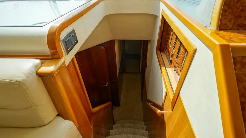 Laurie Lu Yacht Photos Pics Interior staircase of 2002 Viking Princess 68 yacht, featuring wood paneling and carpeted steps.