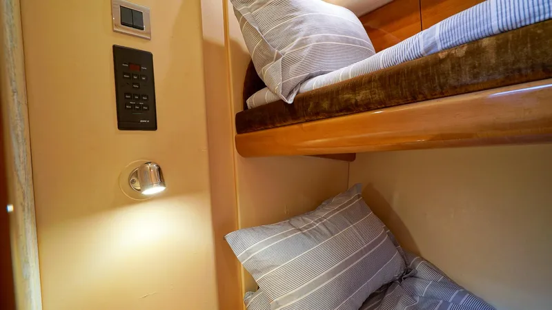 Laurie Lu Yacht Photos Pics Bunk beds in 2002 Viking Princess 68 yacht cabin with striped bedding and wall-mounted light.