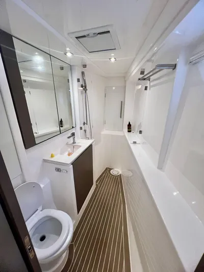 Win Win Yacht Photos Pics Modern yacht bathroom with sleek fixtures, mirror, and wooden flooring, Leopard 50, 2022 model.