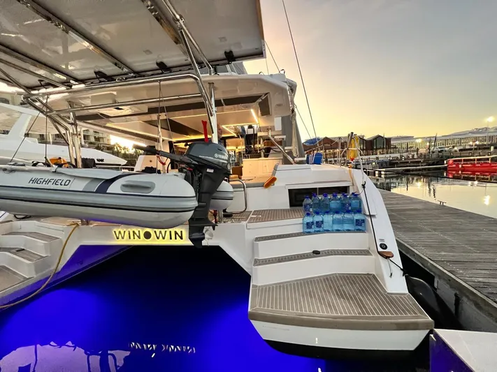 Win Win Yacht Photos Pics Luxury Leopard 50 yacht docked at sunset, featuring a tender and illuminated deck.