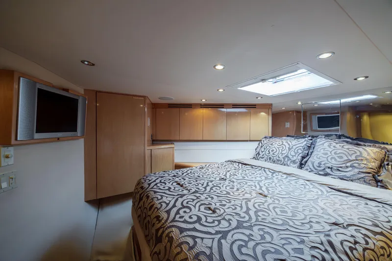 Wet Hooker Yacht Photos Pics Luxurious bedroom interior of 2003 Hatteras 60 Convertible yacht with elegant bedding and modern amenities.