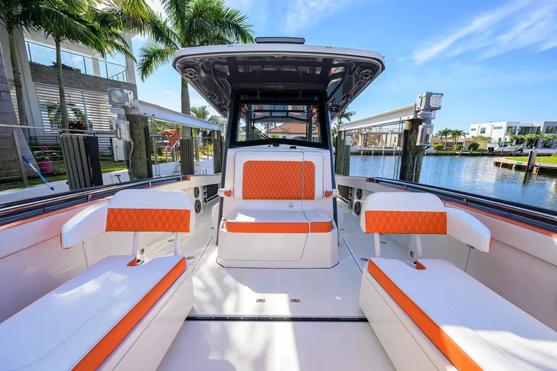  Yacht Photos Pics 2022 World Cat 400 CC-X boat interior with orange and white seating, docked by palm trees.