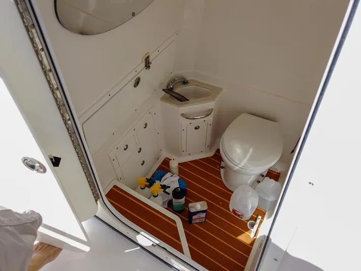  Yacht Photos Pics 2015 Edgewater 320CC boat bathroom with sink, toilet, and cleaning supplies on wooden floor.