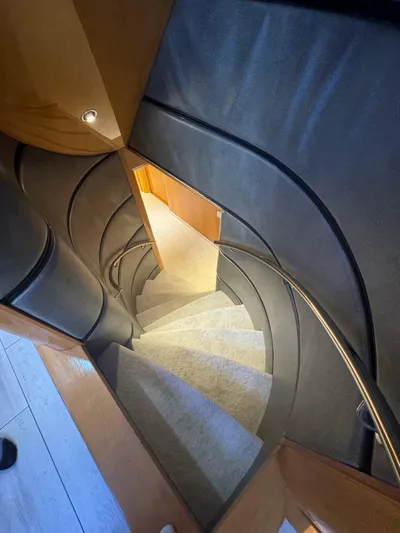  Yacht Photos Pics Spiral staircase inside 2000 Baglietto 116 yacht, featuring elegant wood and metal design.