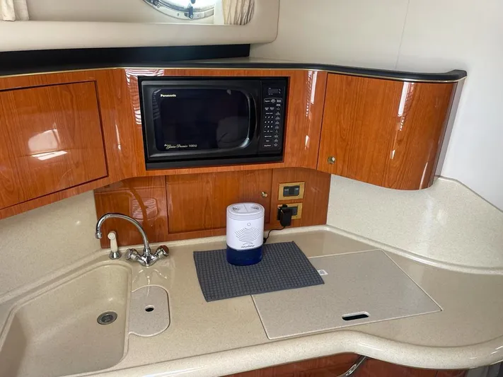 Adagio Yacht Photos Pics 1999 Sea Ray 380 Sundancer kitchen with microwave, sink, and wooden cabinetry.