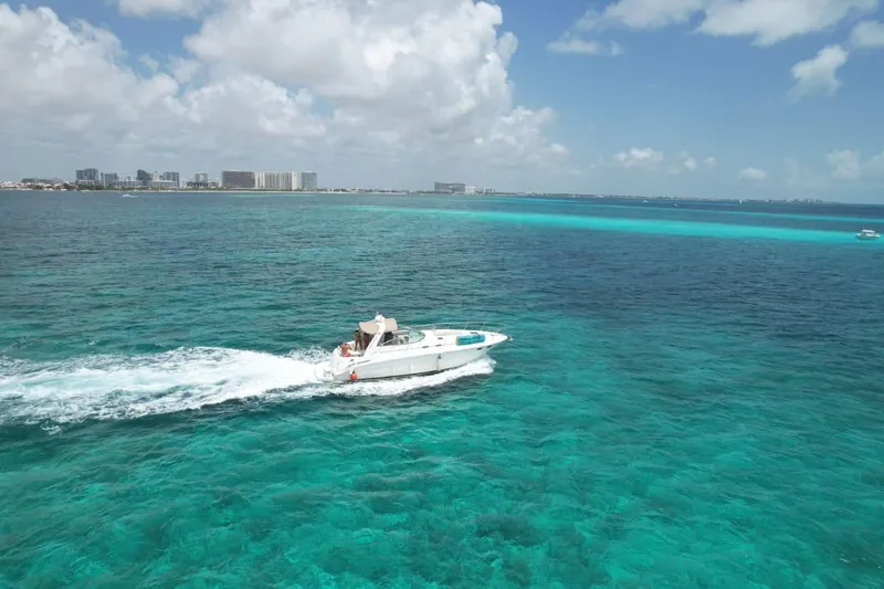 Adagio Yacht Photos Pics 1999 Sea Ray 380 Sundancer cruising on clear turquoise ocean near city skyline.