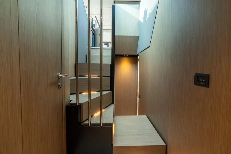  Yacht Photos Pics Modern interior staircase of 2023 Ferretti Yachts 720, featuring sleek wood paneling.
