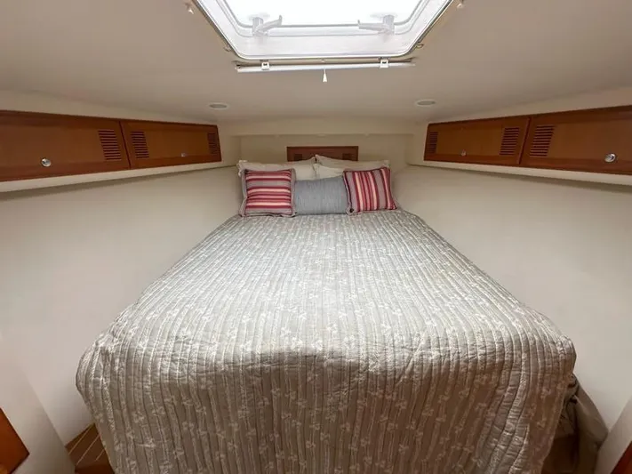 Tuna Daze Yacht Photos Pics 2004 Cabo Express cabin with cozy bed, striped pillows, and wooden storage cabinets.