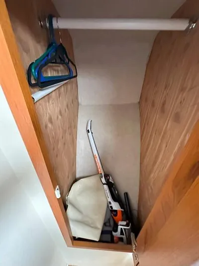 Tuna Daze Yacht Photos Pics Small wooden closet with hangers and a stored chainsaw, Cabo Express 2004 model.