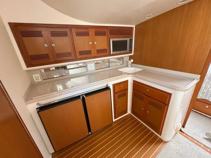Tuna Daze Yacht Photos Pics 2004 Cabo Express boat kitchen with wood cabinets, microwave, and compact fridge.