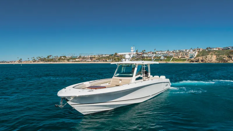 Robin Ann Yacht Photos Pics 2018 Boston Whaler 380 Outrage cruising on blue ocean near coastal homes.