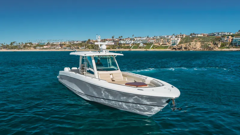 Robin Ann Yacht Photos Pics 2018 Boston Whaler 380 Outrage boat on clear blue water near coastal homes.