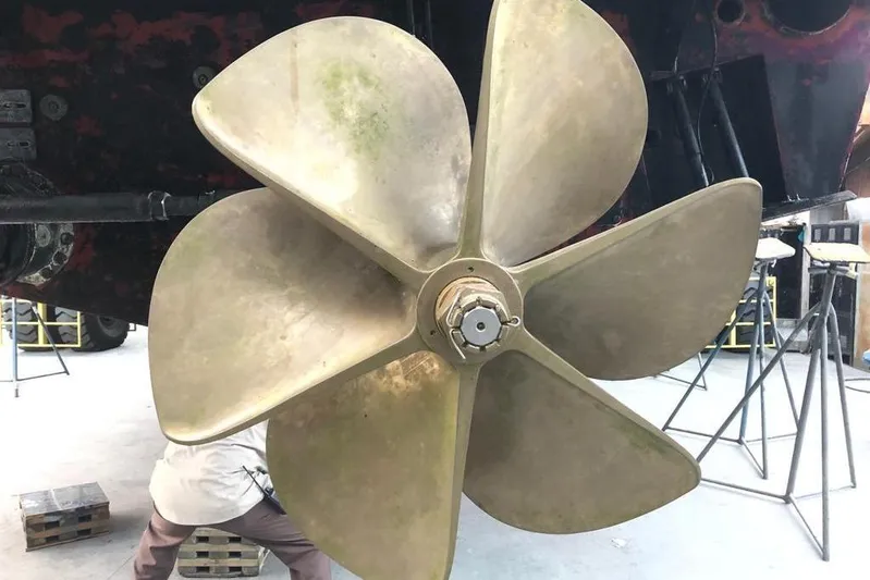 Argonaut Yacht Photos Pics Large brass propeller of a 2011 Baia ONE HUNDRED yacht in a workshop setting.