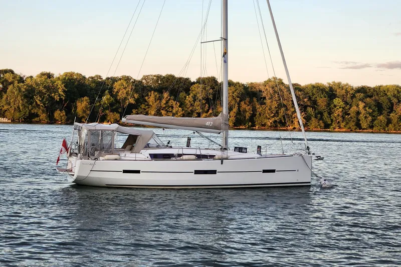  Yacht Photos Pics 2019 Dufour Grand Large 412 Grand Prix sailboat on calm water, lush trees in background.