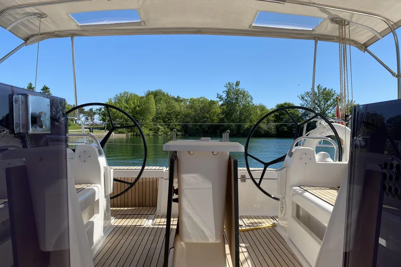  Yacht Photos Pics 2019 Dufour Grand Large 412 Grand Prix yacht cockpit with dual steering wheels, docked by a serene lake.