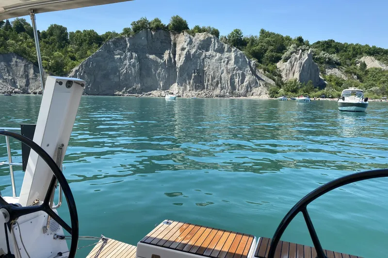  Yacht Photos Pics View from 2019 Dufour Grand Large 412 sailboat, overlooking serene waters and rocky cliffs.