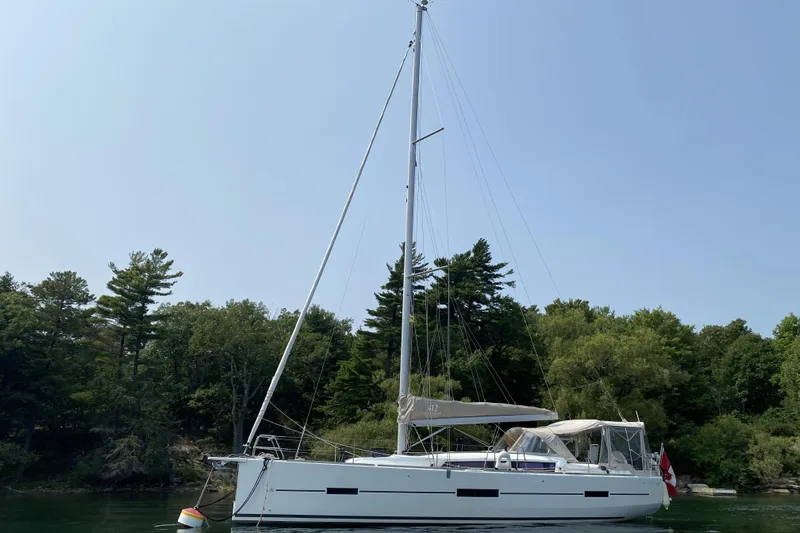  Yacht Photos Pics 2019 Dufour Grand Large 412 Grand Prix sailboat anchored near lush green trees.
