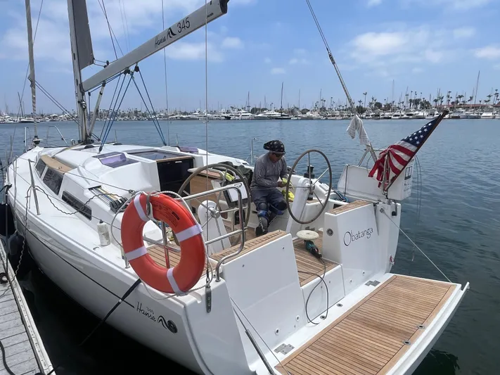 Obatanga Yacht Photos Pics 2014 Hanse 345 sailboat docked, featuring American flag and life preserver, in a marina setting.